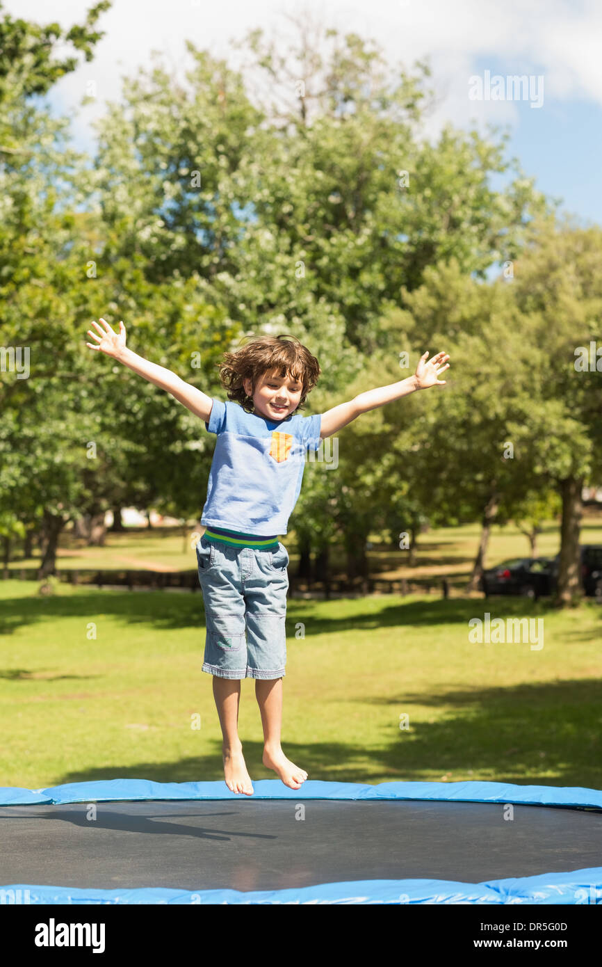 Fröhlicher Junge hoch springen auf dem Trampolin im park Stockfoto