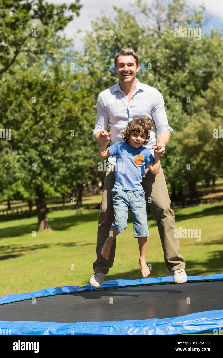 Fröhlicher Junge und Vater hoch springen auf dem Trampolin im park Stockfoto
