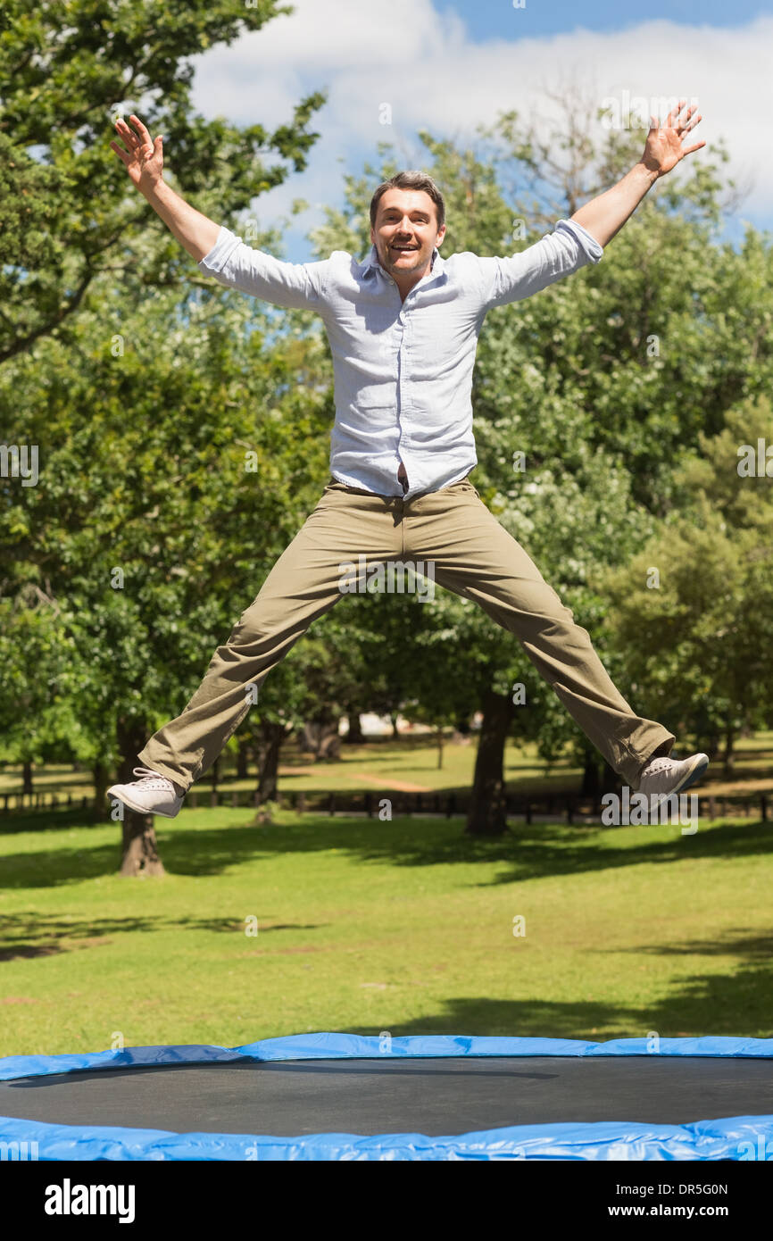 Glücklicher Mann hoch springen auf dem Trampolin im park Stockfoto