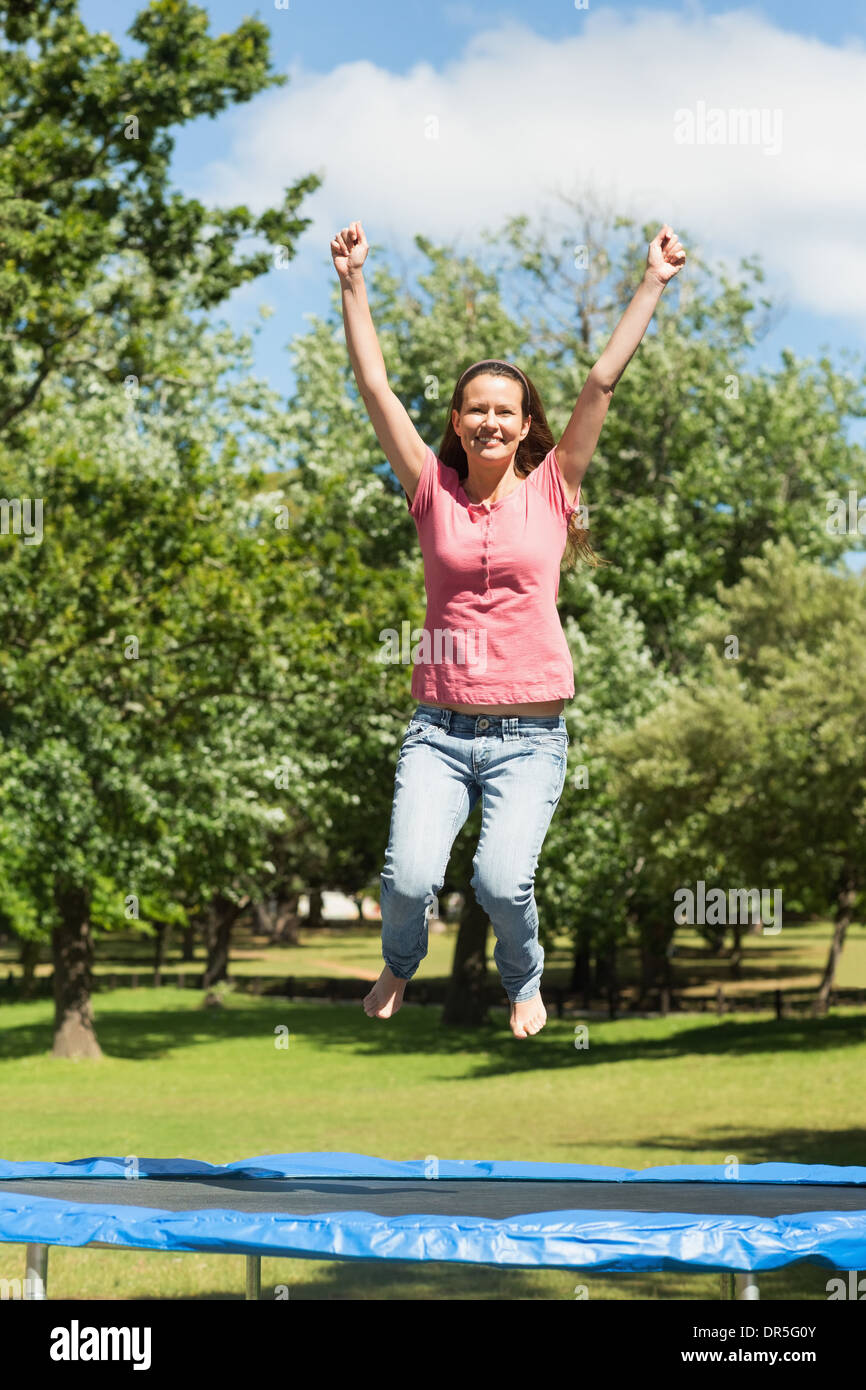 Glückliche Frau hoch springen auf dem Trampolin im park Stockfoto