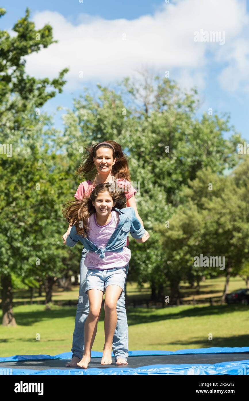 Glückliches Mädchen und Mutter hoch springen auf dem Trampolin im park Stockfoto