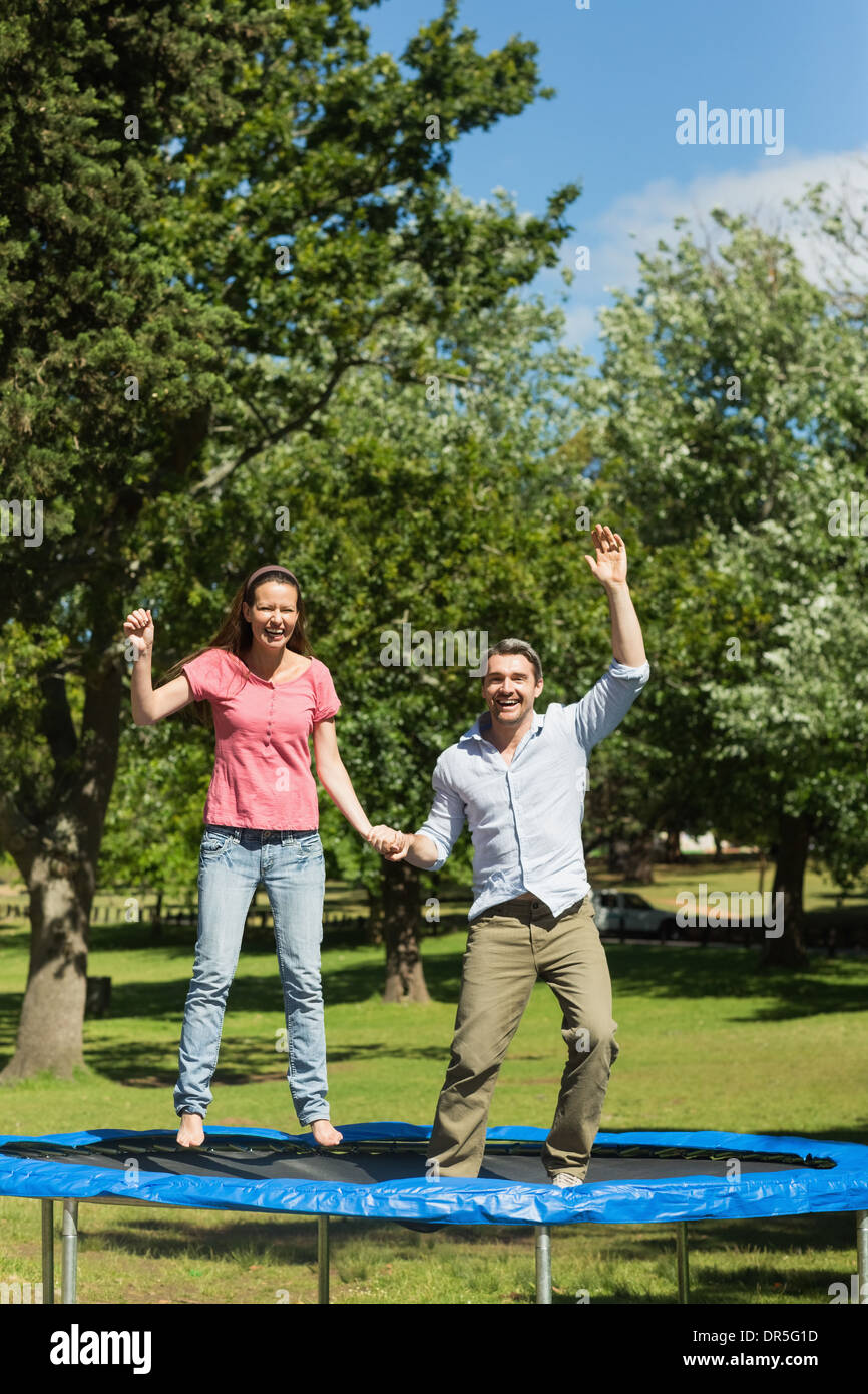 Glückliches Paar hoch springen auf dem Trampolin im park Stockfoto