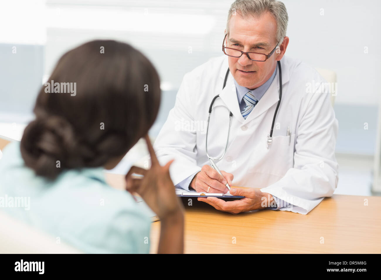 Reife Arzt anhören seiner Patienten und Notizen Stockfoto