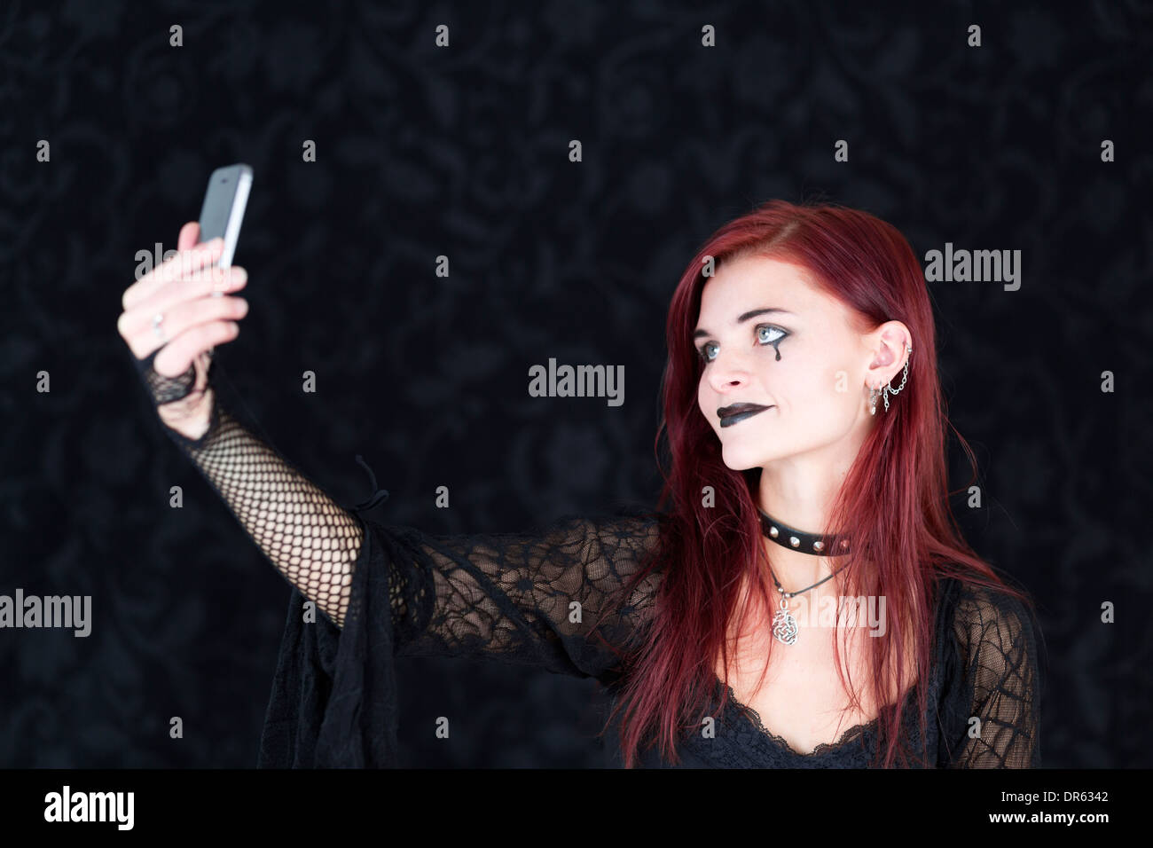Junge Frau trägt gotische Mode fotografieren sich mit smartphone Stockfoto