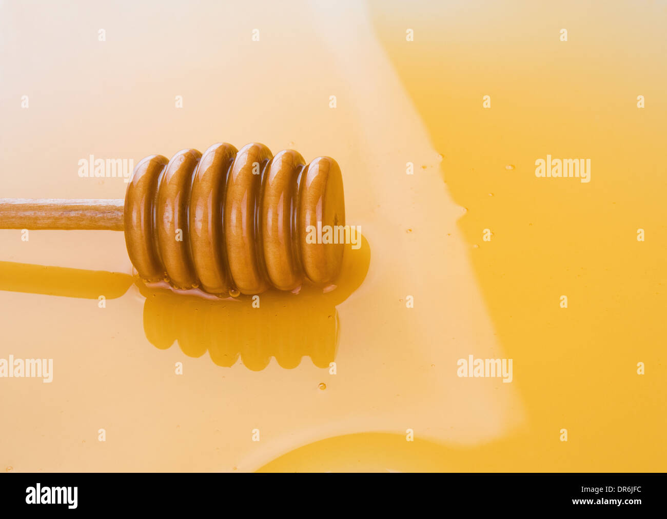 Pfütze des Honigs mit Holzstab als Hintergrund Stockfoto