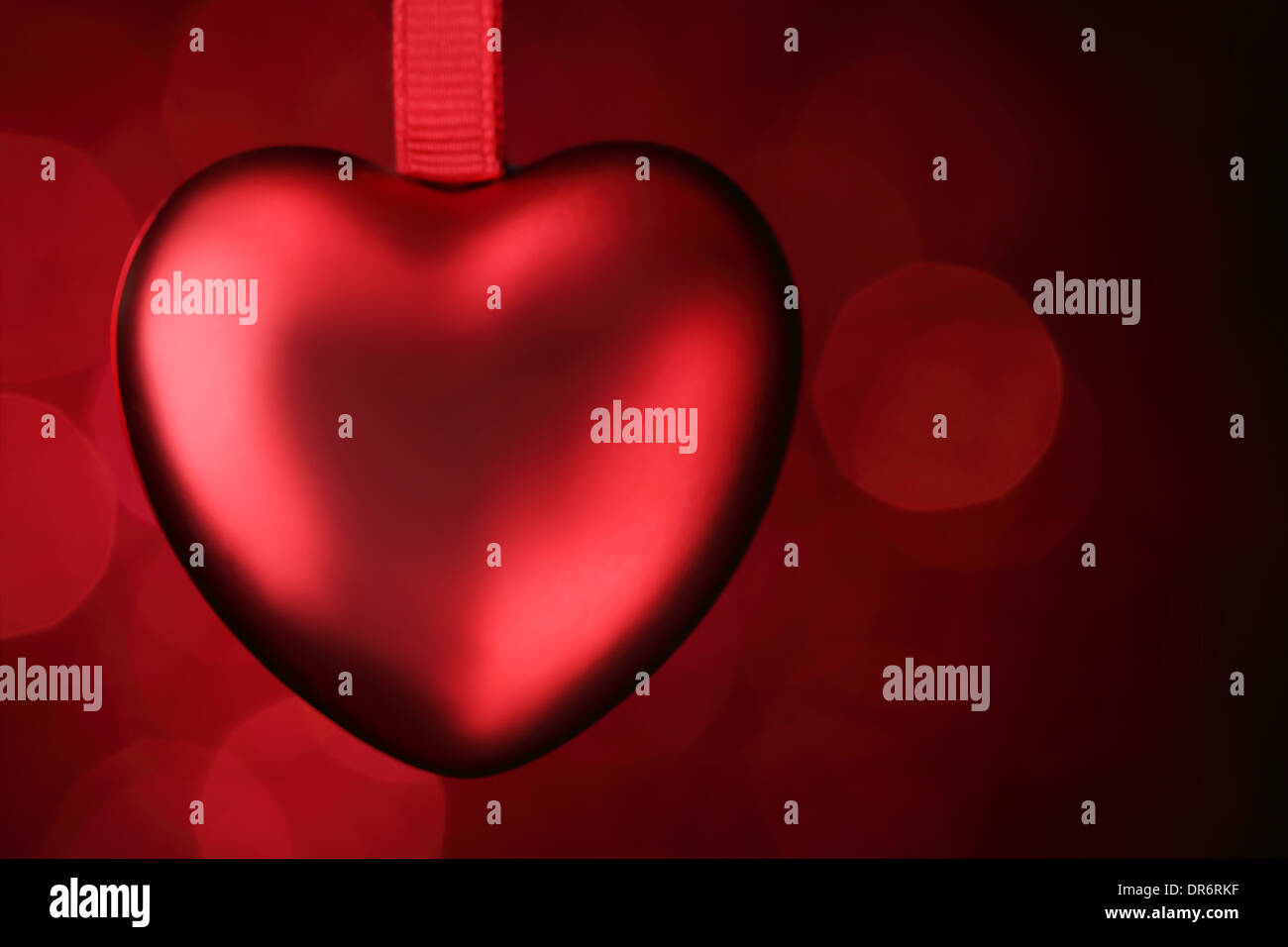Rotes Herz hängend auf rotem Grund Stockfoto
