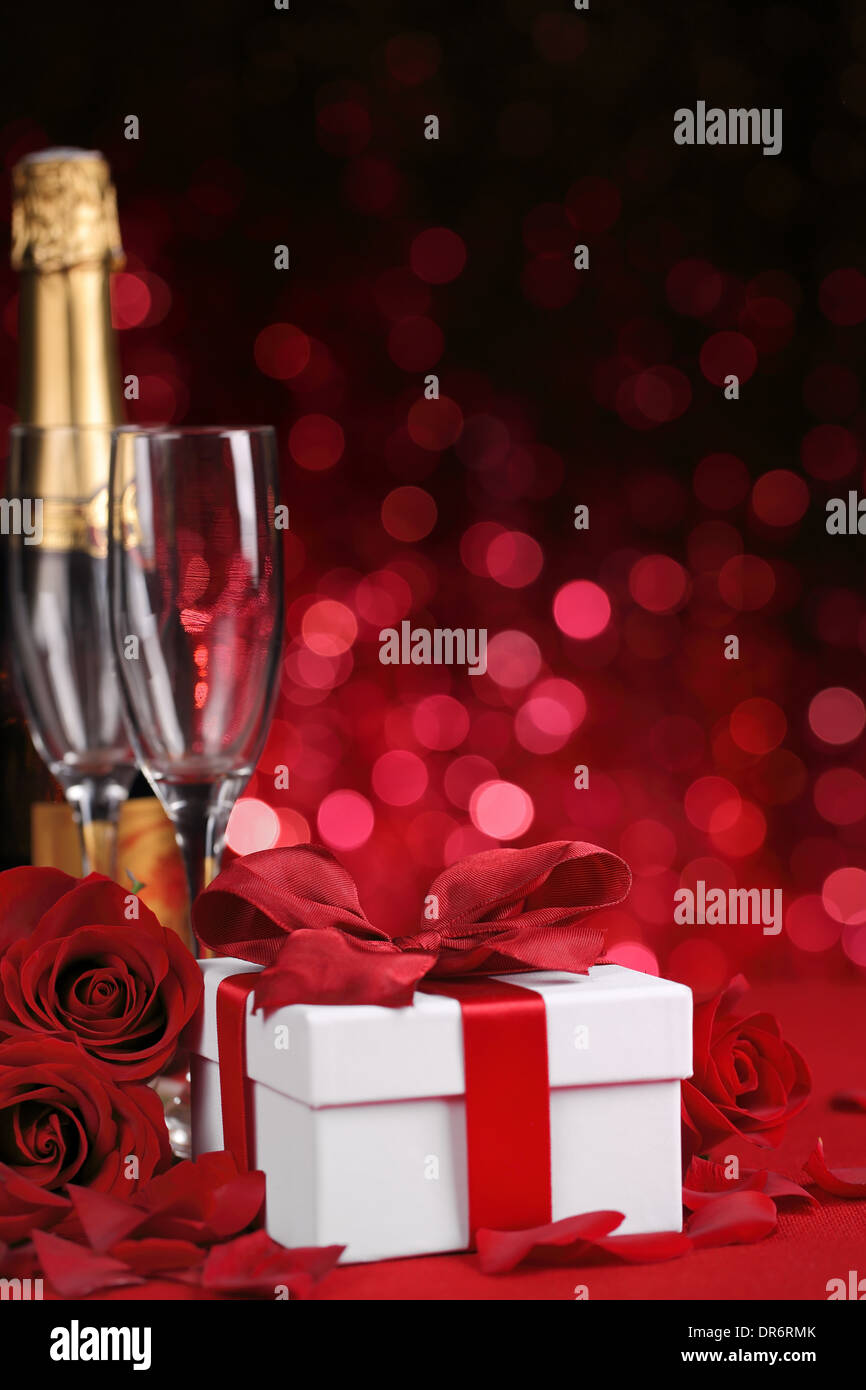 Champagner, Geschenk-Box und Rose auf rotem Grund Stockfoto