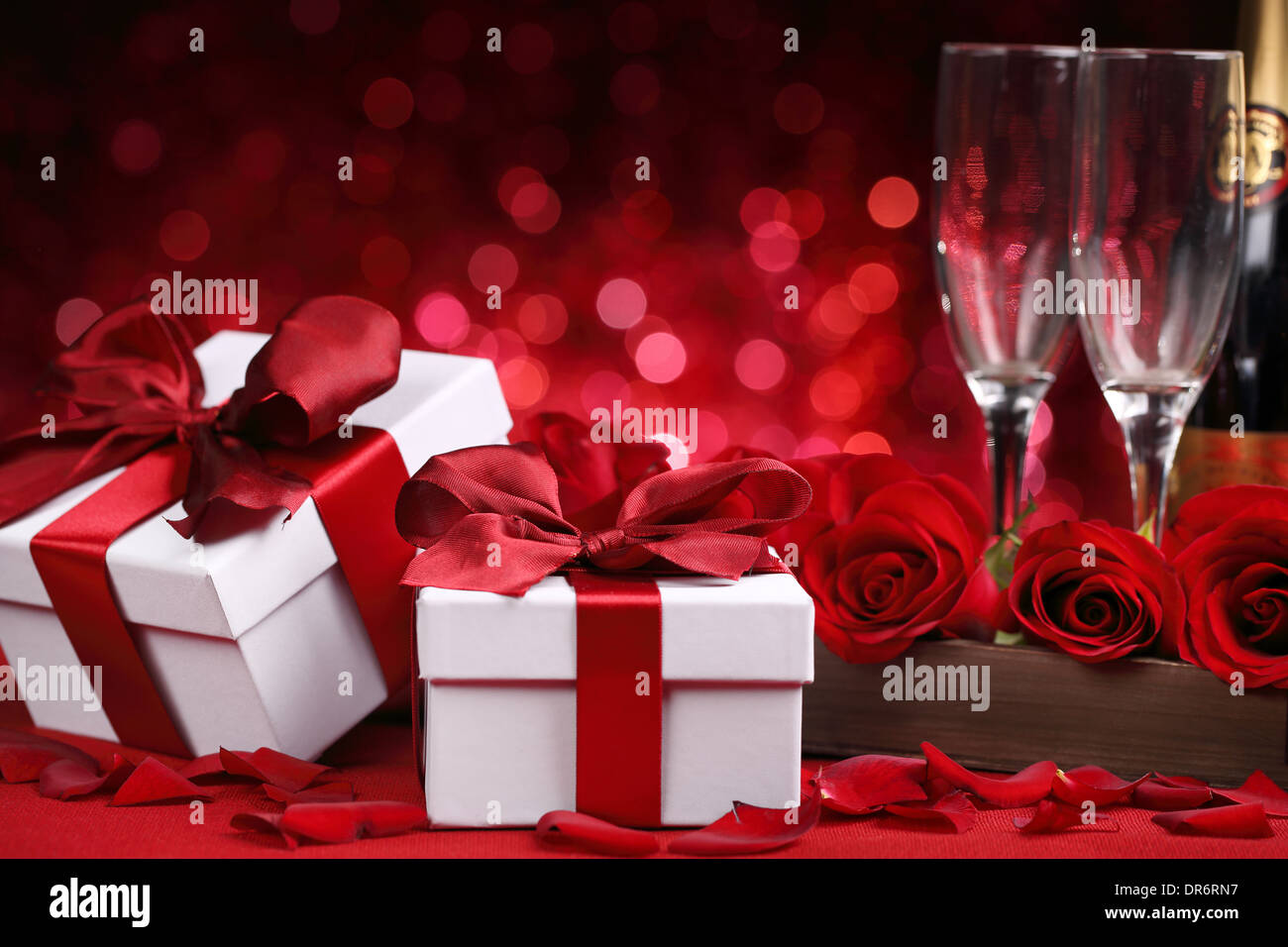 Champagner, Geschenk-Box und Rose auf rotem Grund Stockfoto