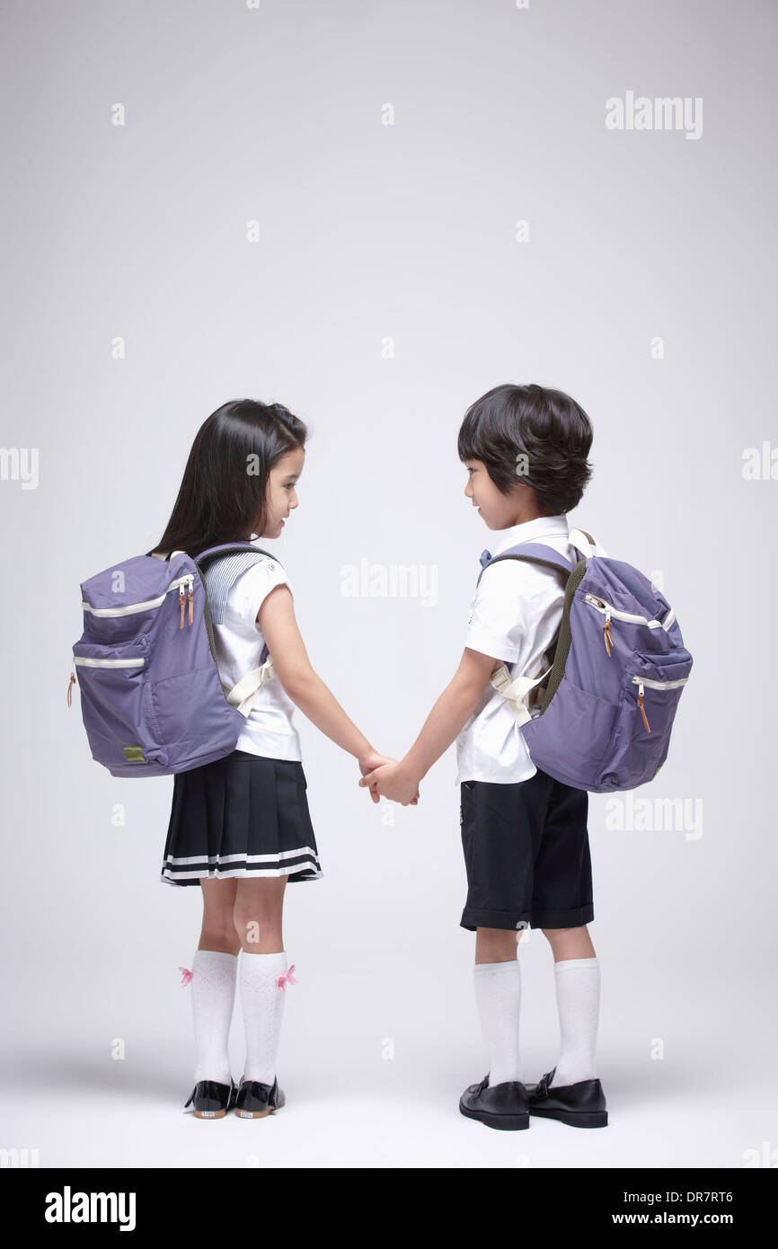 ein Junge und ein Mädchen trägt Schultaschen Hand in Hand Stockfoto
