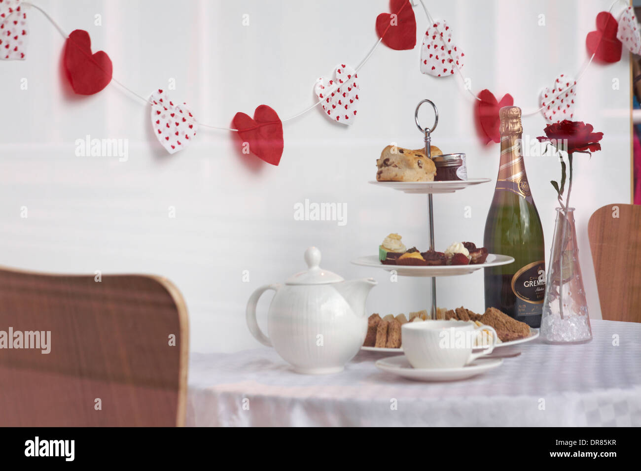 Valentine Anzeige im Fenster in Portsmouth mit Tee, Flasche Sekt, Kuchen und Sandwiches, rote Rose und Herz bunting für Valentines Tag Stockfoto