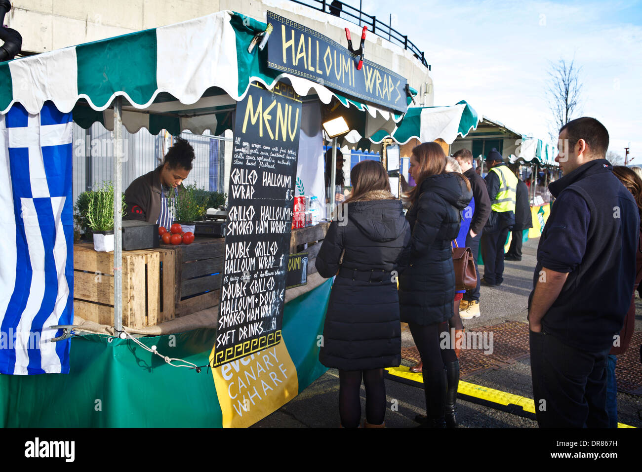 Markt London Essen in Canary Wharf. Anbieter vorbereiten und verkaufen, griechisches Essen Halloumi Verpackungen zu queuing Kunden. UK-Markt ausgehen. Stockfoto