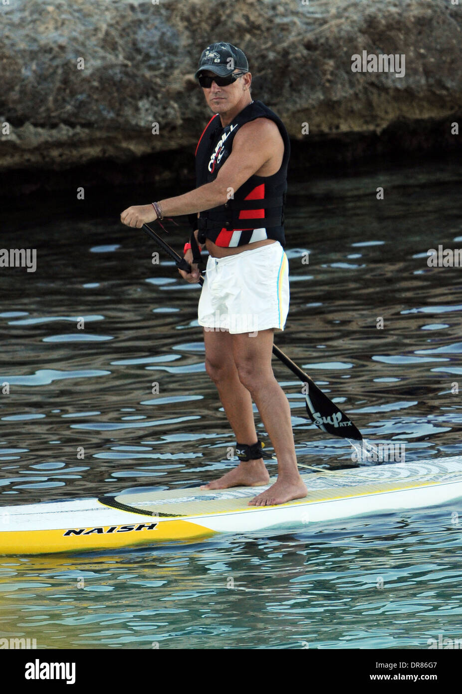 Der Sänger Bruce Springsteen tun Paddlesurf an einem Strand im Urlaub auf Mallorca im Jahr 2013. Stockfoto