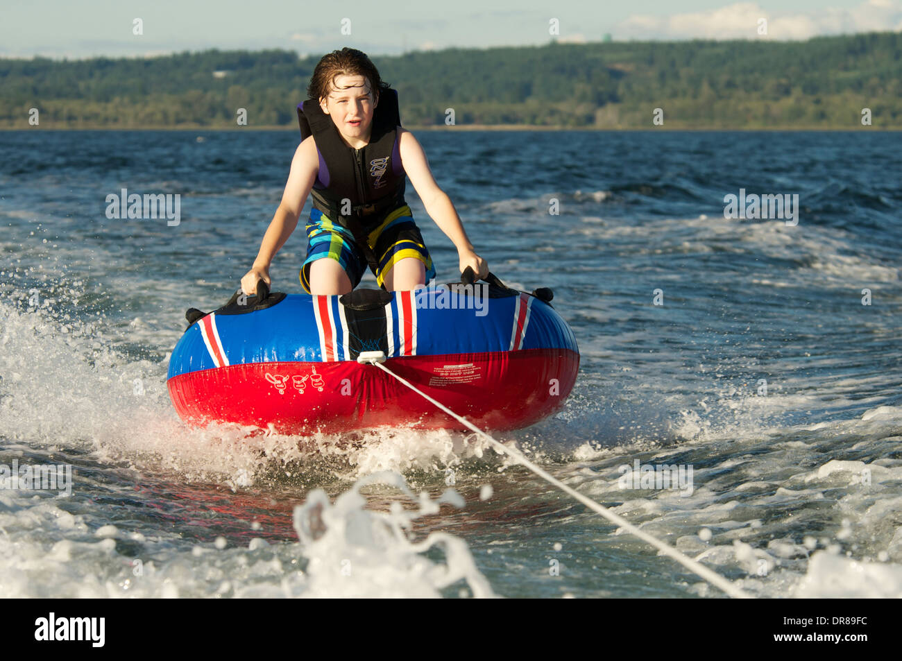 Boy freudig und furchtlos reitet Innenrohr auf See auf Ein sonniger Sommertag Stockfoto