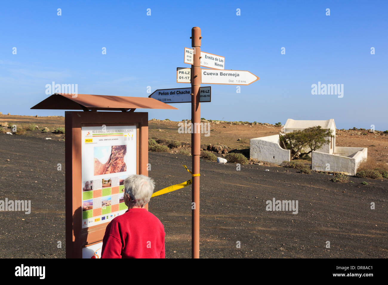Ältere Frau liest touristische Informationen Zeichen zeigt Wanderwege an Famara Aussichtspunkt. Haria Lanzarote Kanarische Inseln Spanien Stockfoto