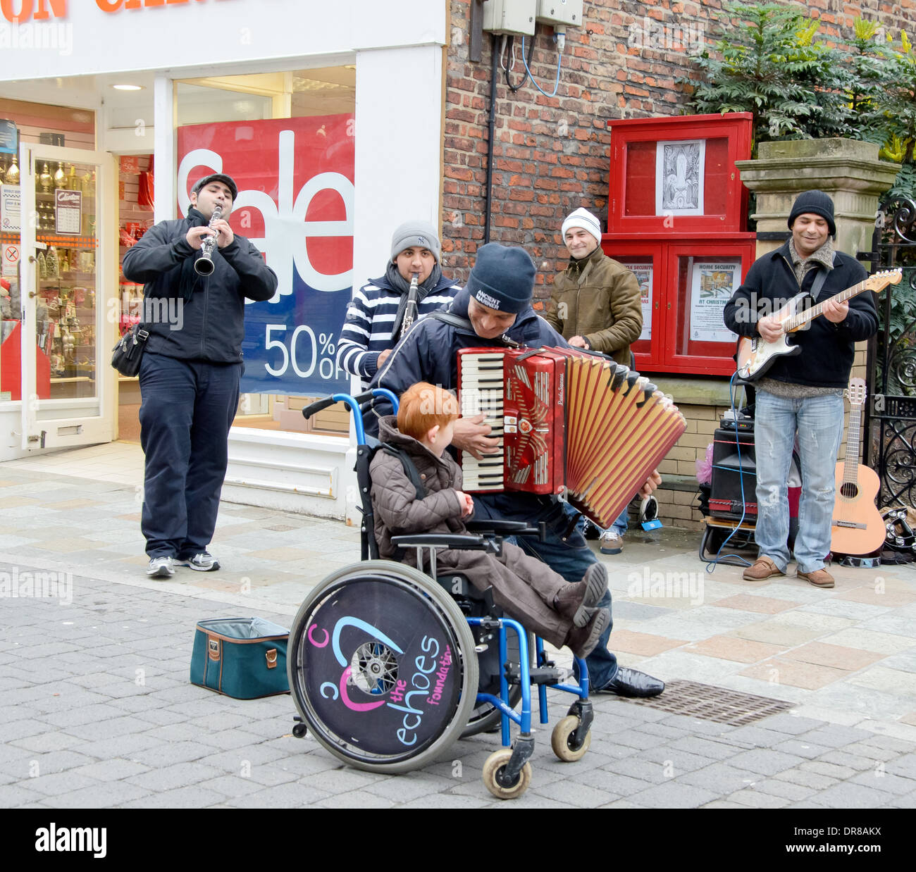 Kind im Rollstuhl durch Straßenmusiker unterhalten Stockfoto