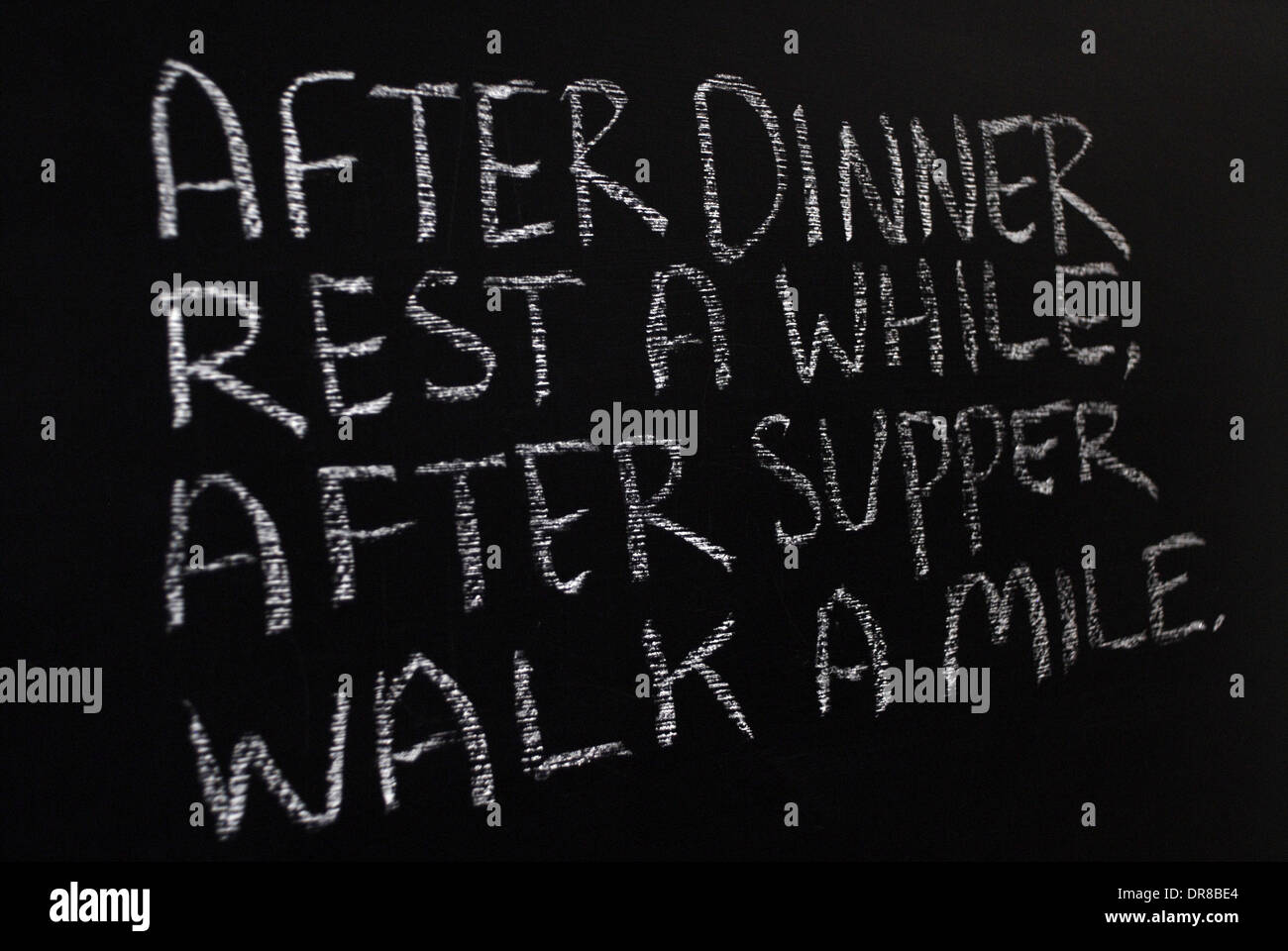 Kreide schreiben - nach dem Abendessen eine Weile ausruhen, nach dem Abendessen gehen eine Meile. -Wörter auf Tafel geschrieben. Stockfoto