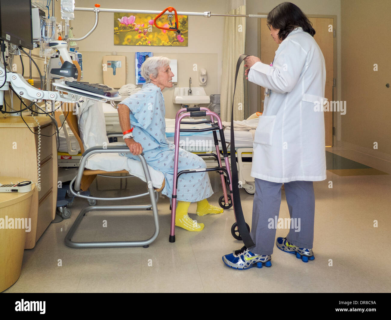 Eine Ergotherapeutin lehrt erholt Hüft Chirurgie Patienten in einem Krankenhaus von Südkalifornien zu stehen. Stockfoto