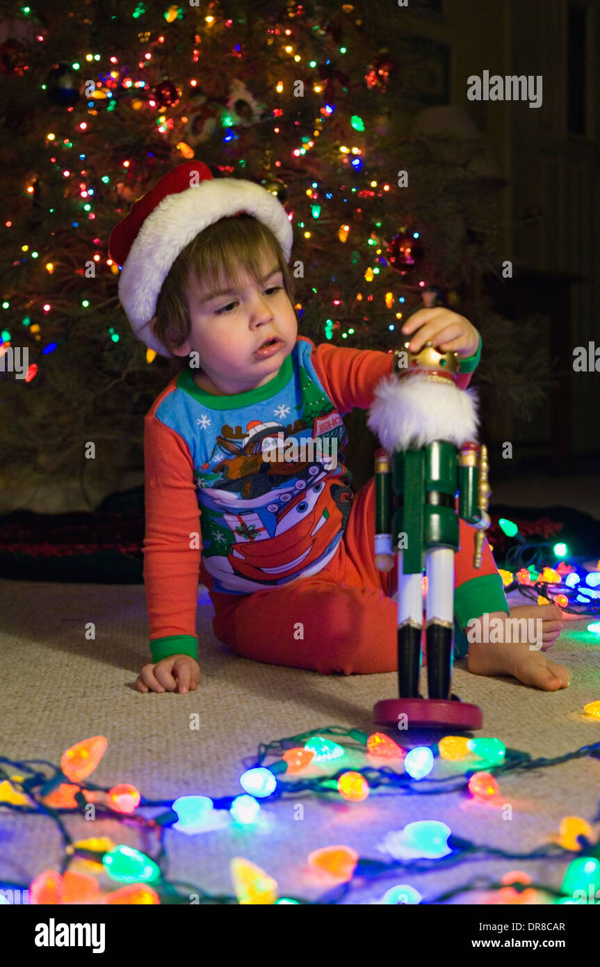 Kleinkind spielt mit Nussknacker neben Weihnachtsbaum Stockfoto