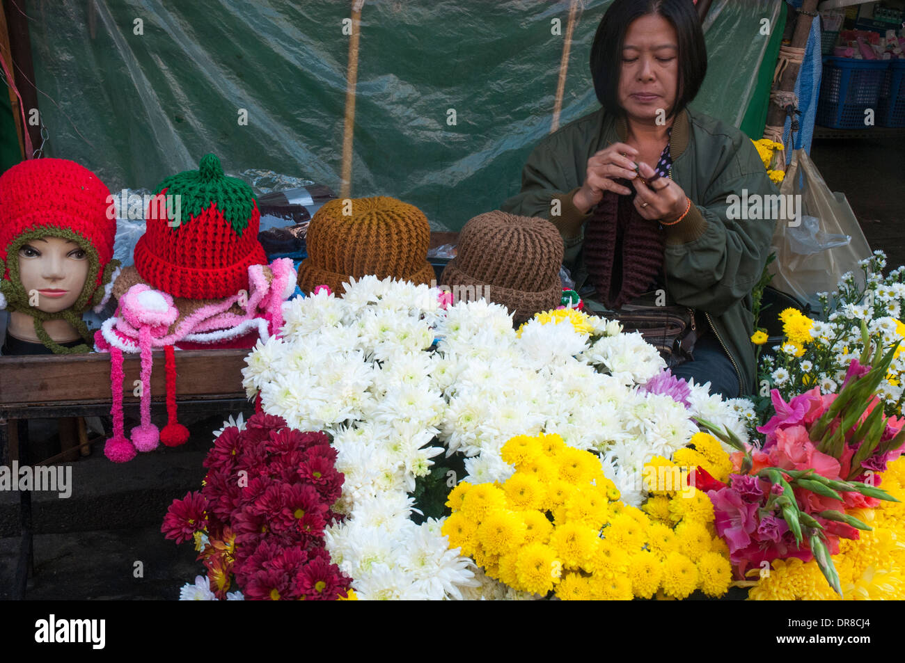 Ein Kreditor stricken Wolle Mützen zwischen Verkäufen am Blumenmarkt, Chiang Mai, Thailand Stockfoto