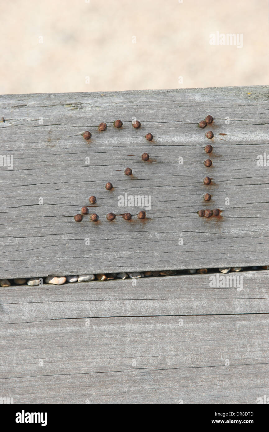 Nummer 21 in Rusty Nails nagelt in Holzbruchwasser in Winchelsea Beach, East Sussex, Großbritannien Stockfoto