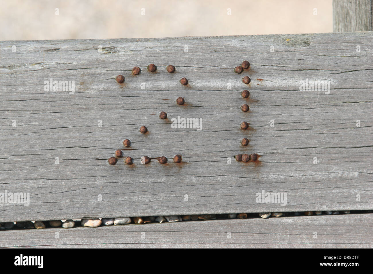 Nummer 21 in Rusty Nails nagelt in Holzbruchwasser in Winchelsea Beach, East Sussex, Großbritannien Stockfoto