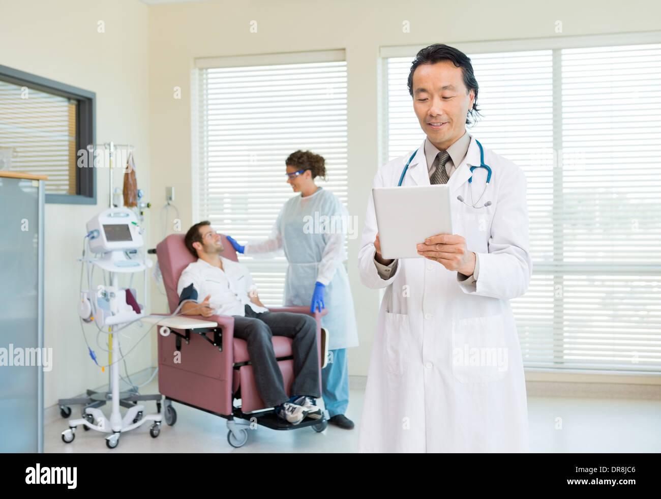Arzt mit Digital-Tablette In Chemo-Raum Stockfoto
