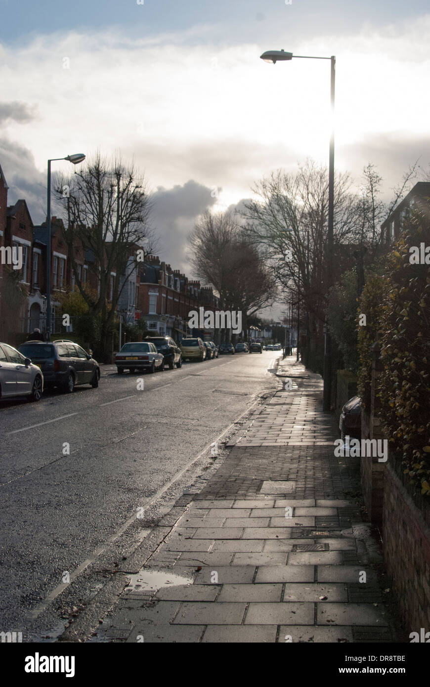 Eine Straße in Kew; Aufnahme in Richtung der Sonne an einem Wintertag, starke Highlights und interessante, düsteren Wolkenformationen. Stockfoto