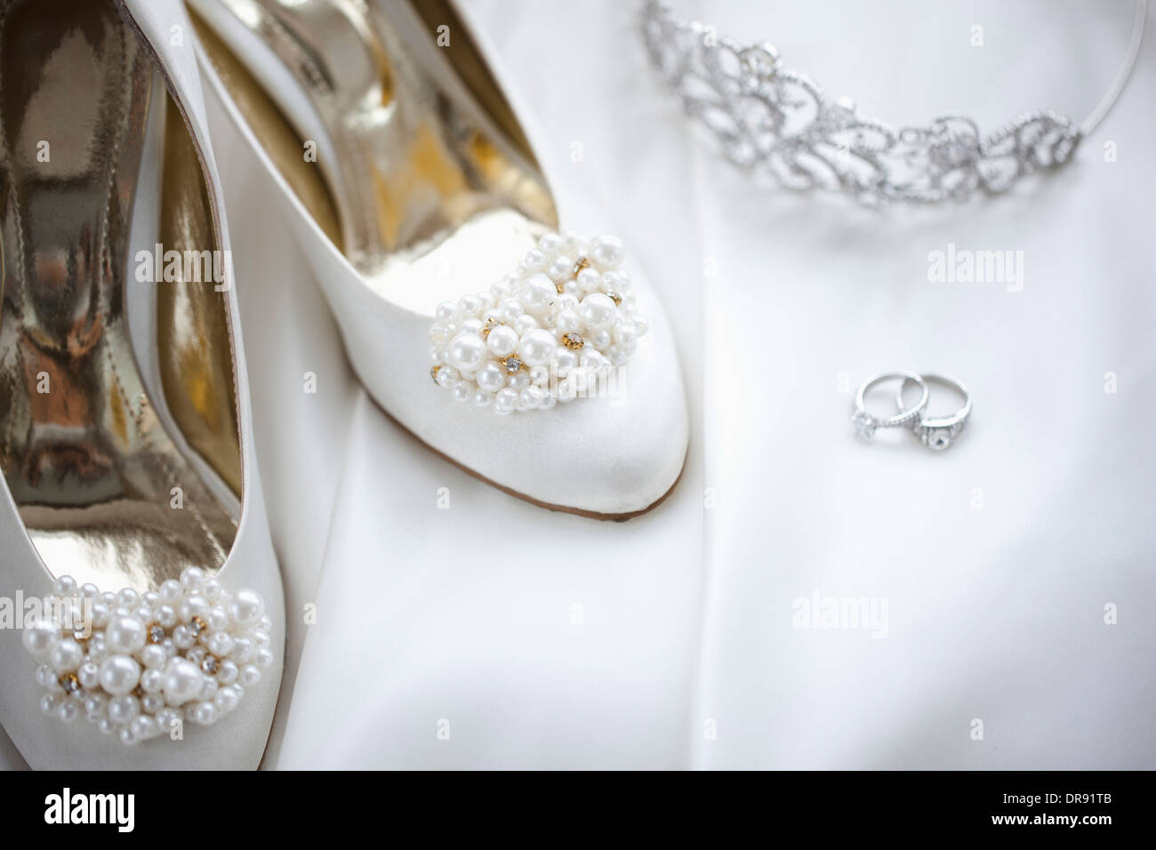 Trauringe und Heels auf Hochzeitskleid Stockfoto