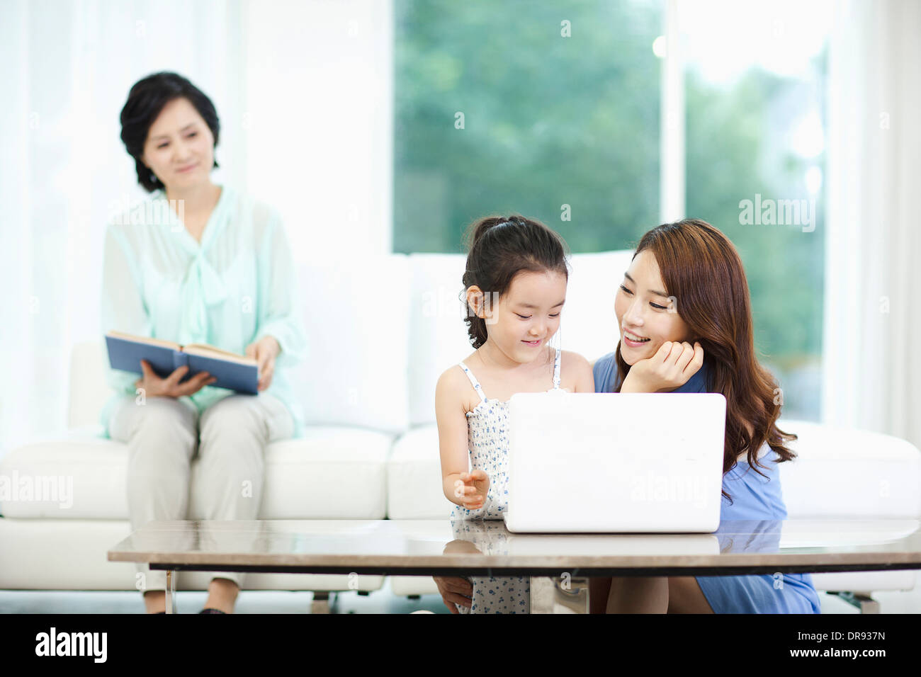 eine Frau, Tochter und Enkelin mit Laptop beobachten Stockfoto