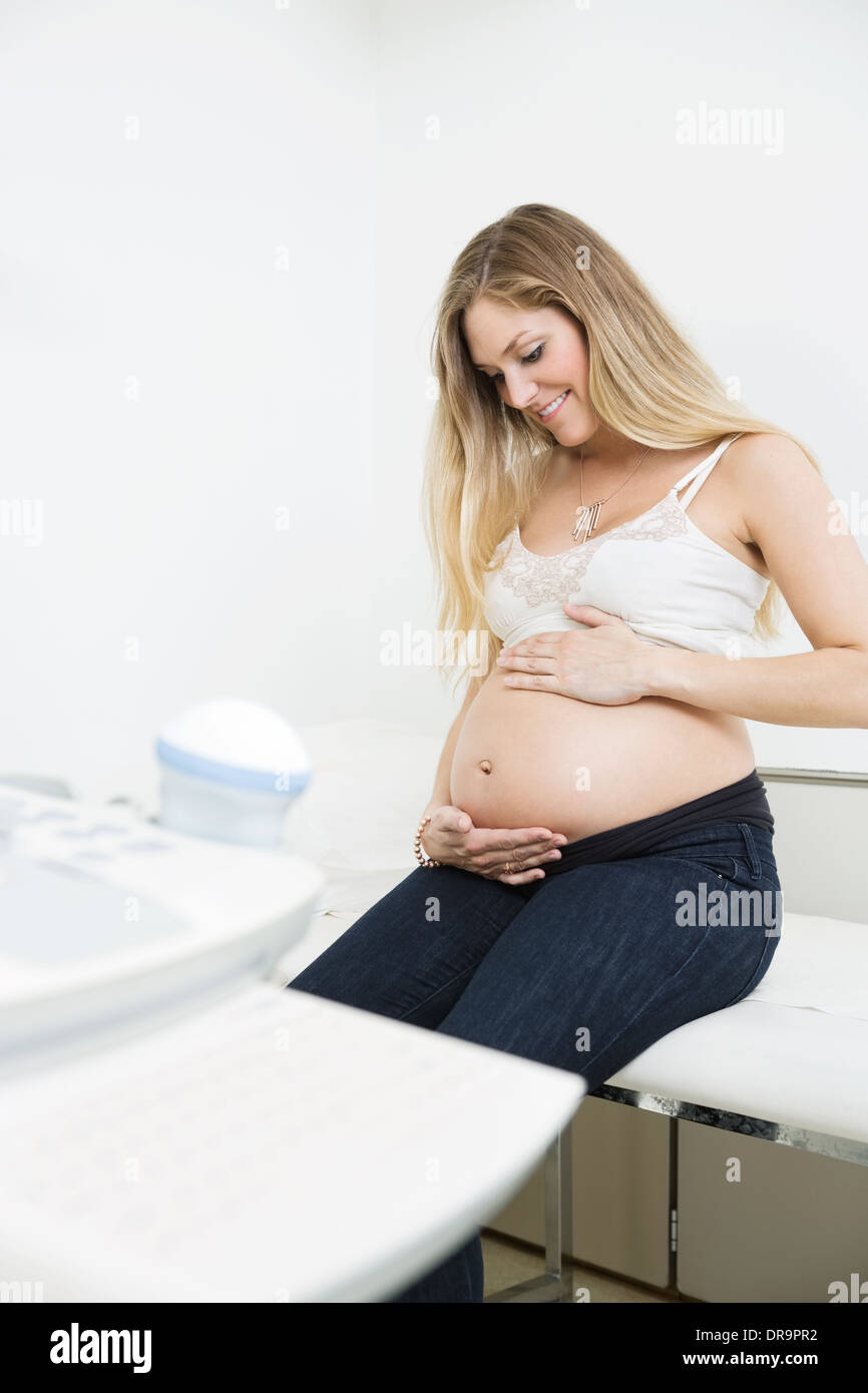 Schwangere Frau streichelt Bauch In Klinik Stockfoto