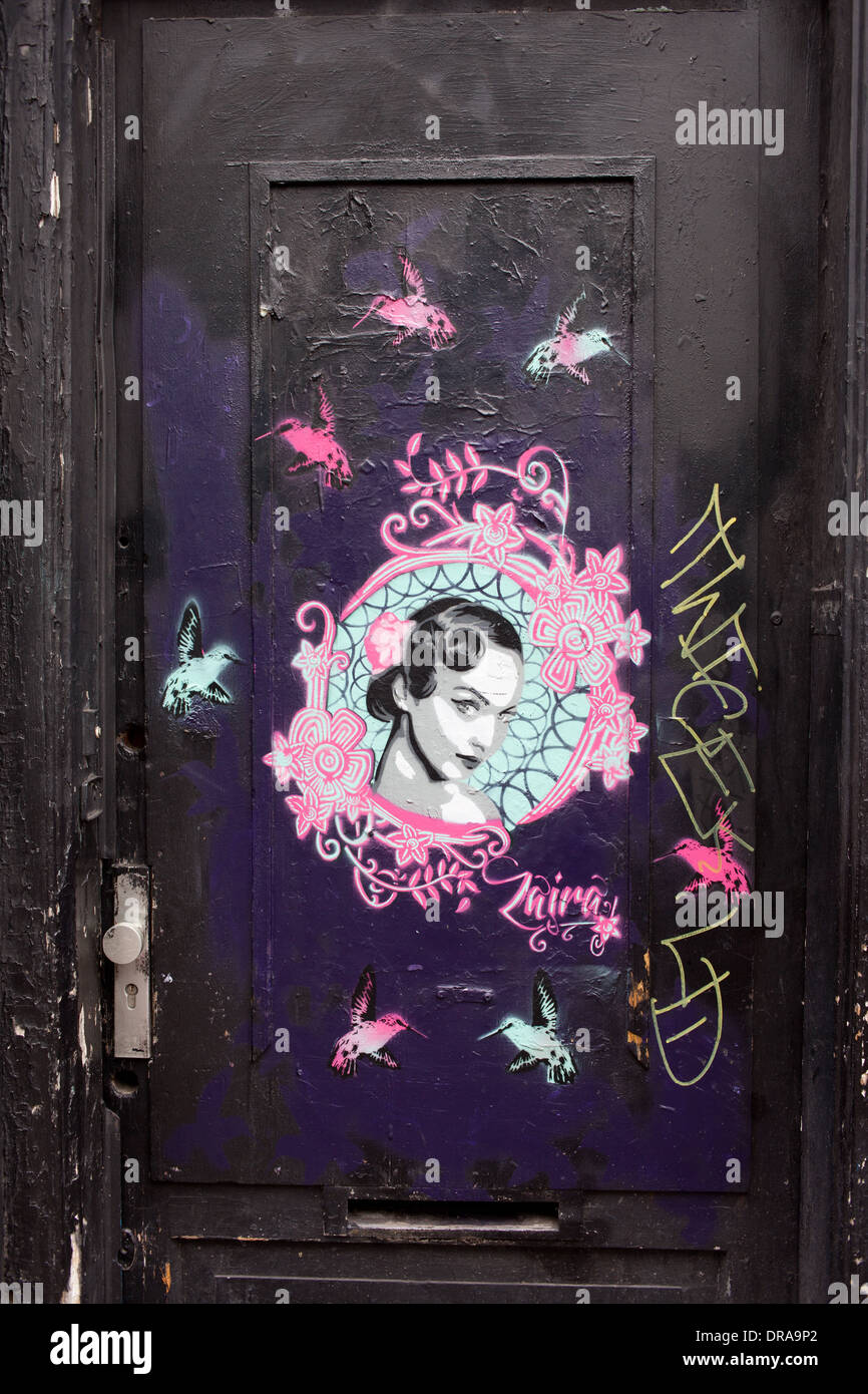 Retro-Frau Porträt verzierten Rahmen umgeben von Kolibris, Graffiti auf einem schwarzen Tor in Amsterdam, Niederlande. Stockfoto