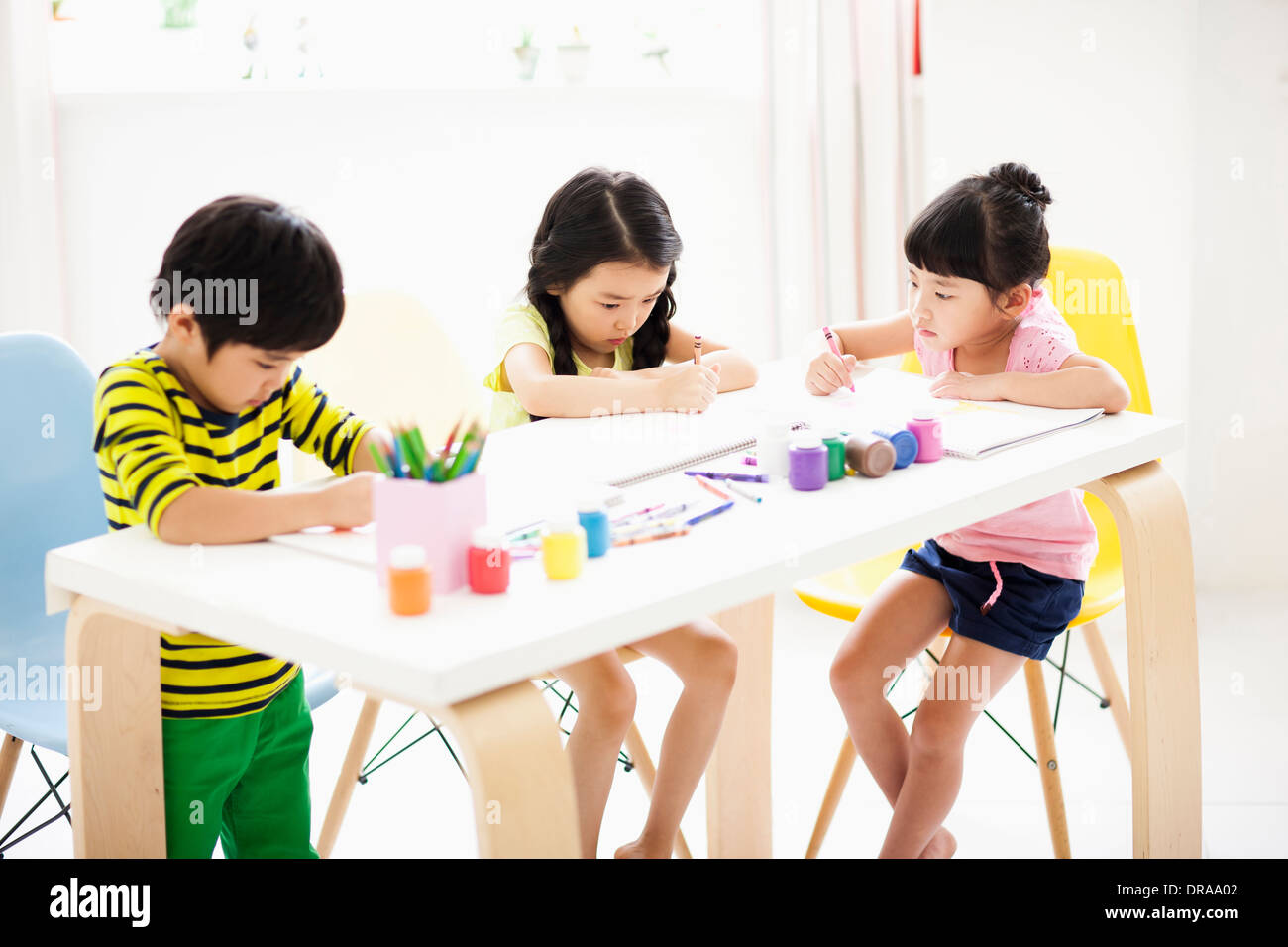 Kinder am Tisch mit Skizzenbüchern und Buntstifte Stockfoto