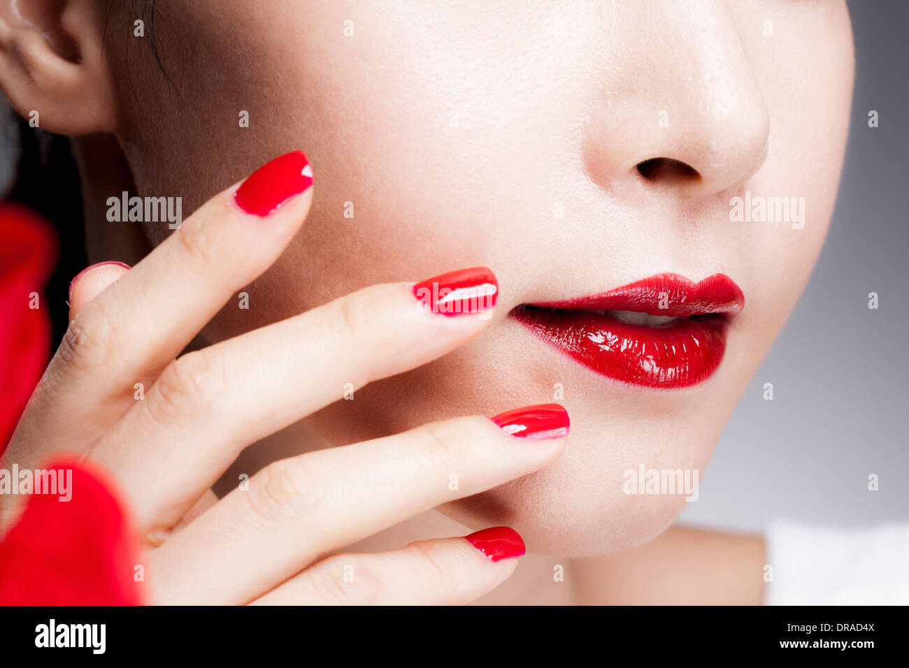 Nahaufnahme Bild von einer Frau rote Nägel auf ein Gesicht mit roten Lippen Stockfoto