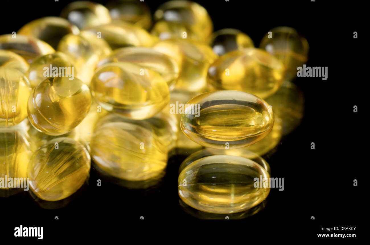 Dorschleber-Öl-Kapseln auf einem schwarzen Hintergrund gespiegelt Stockfoto