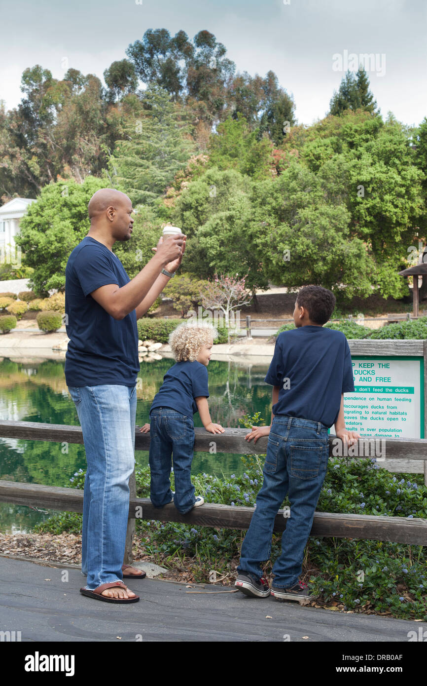 Vater mit Kindern stützte sich auf Holzzaun in Menlo Park Stockfoto