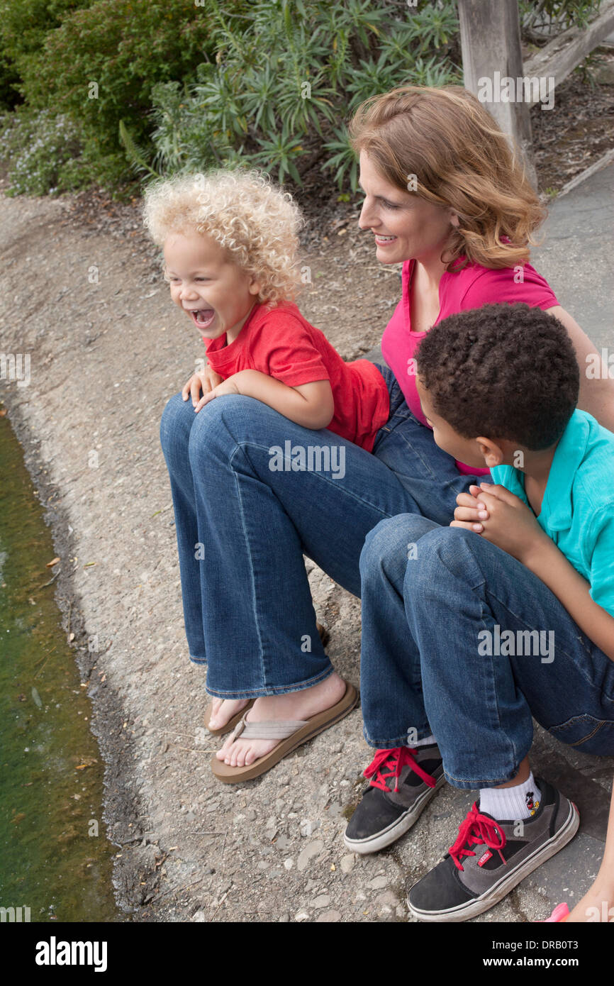 Glückliche Mutter mit Kindern am Flussufer. Stockfoto