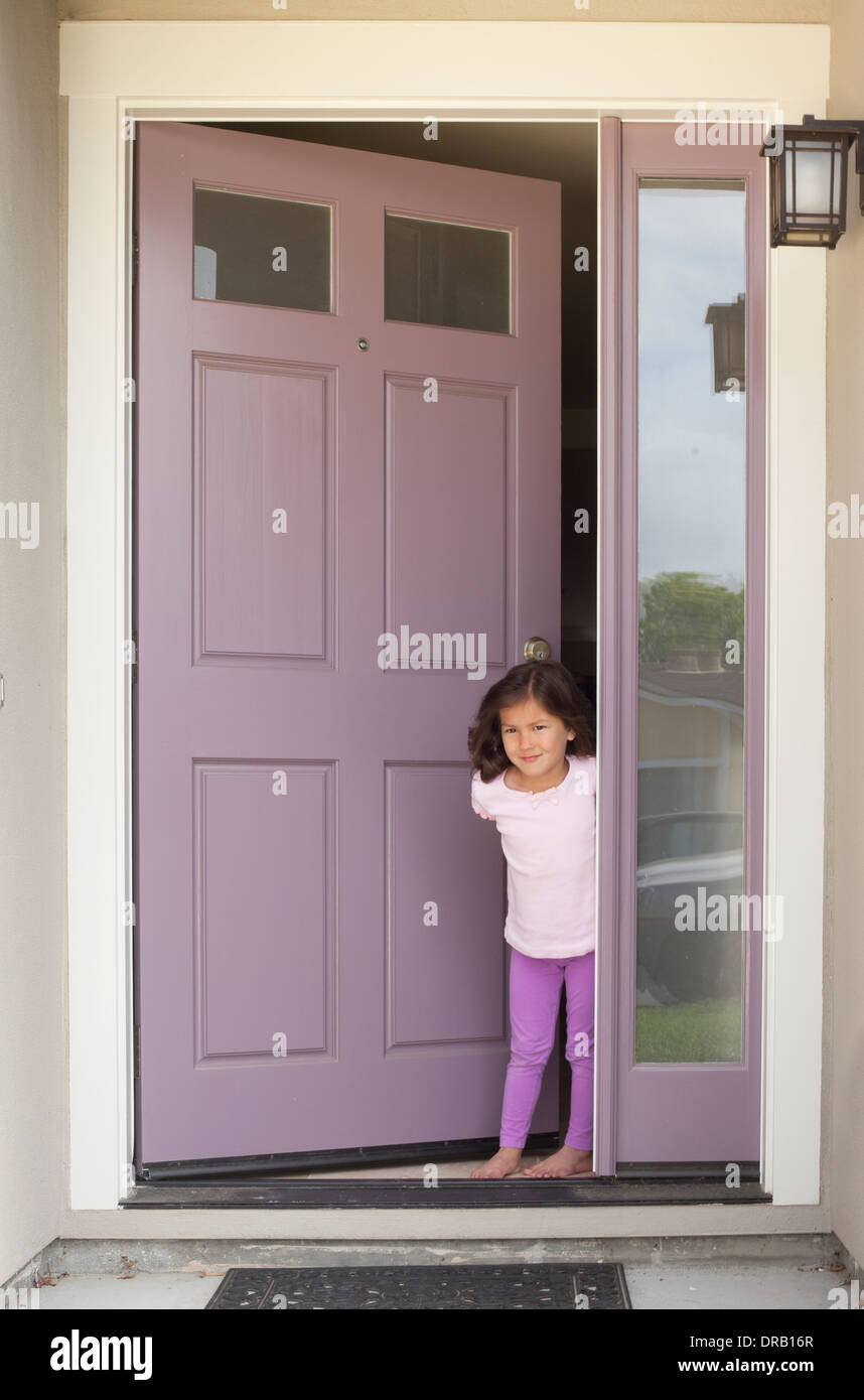Kleines Mädchen mit offener Tür am Eingang des Hauses Stockfoto