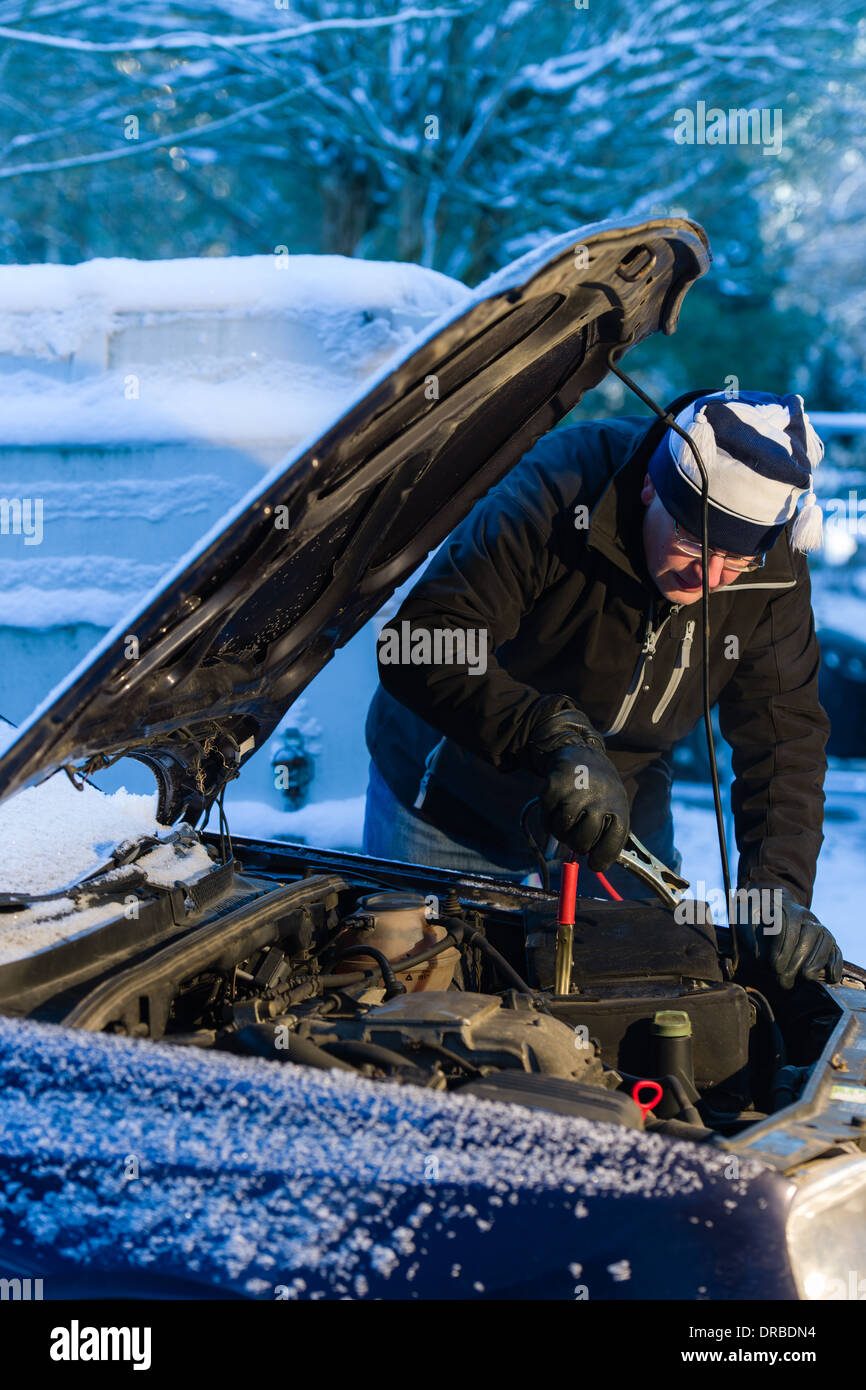 Ein Mann Haken Booster Kabel um die entladene Batterie, kalten Wintertag Stockfoto