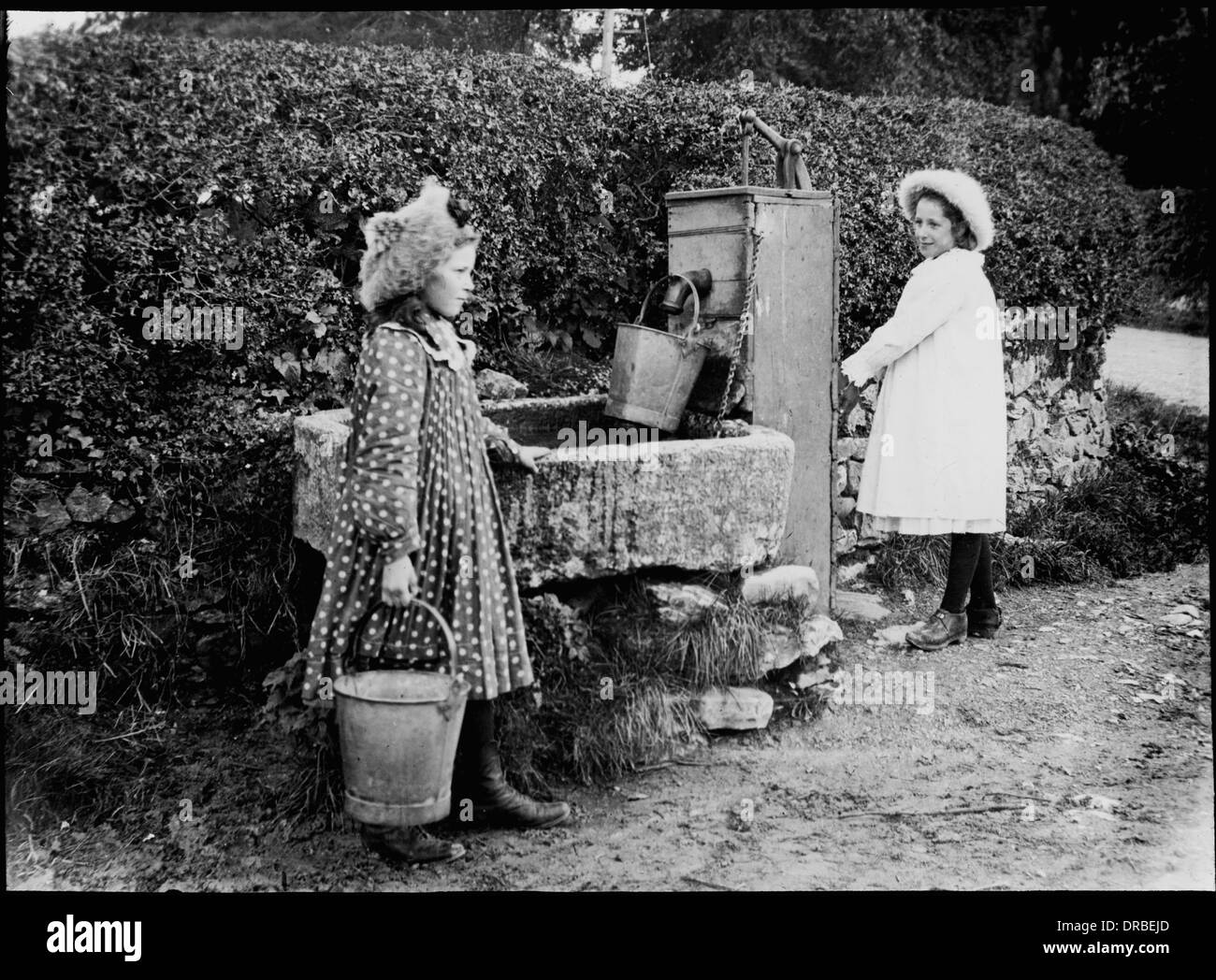 Porträt von zwei Mädchen an der Dorf-Wasserpumpe. Laterne Objektträger ein Foto aufgenommen im Jahre 1905. Beschriftete "Familie Thompson an Pumpe". Beetham, Cumbria (dann Westmorland), Lake District, England. Stockfoto