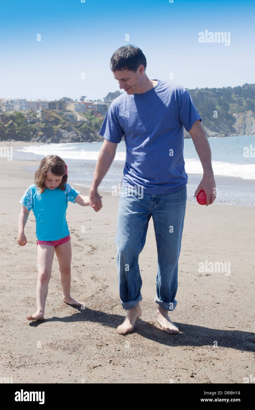 Vater mit Tochter Hand in Hand und zusammen spazieren am Strand Stockfoto