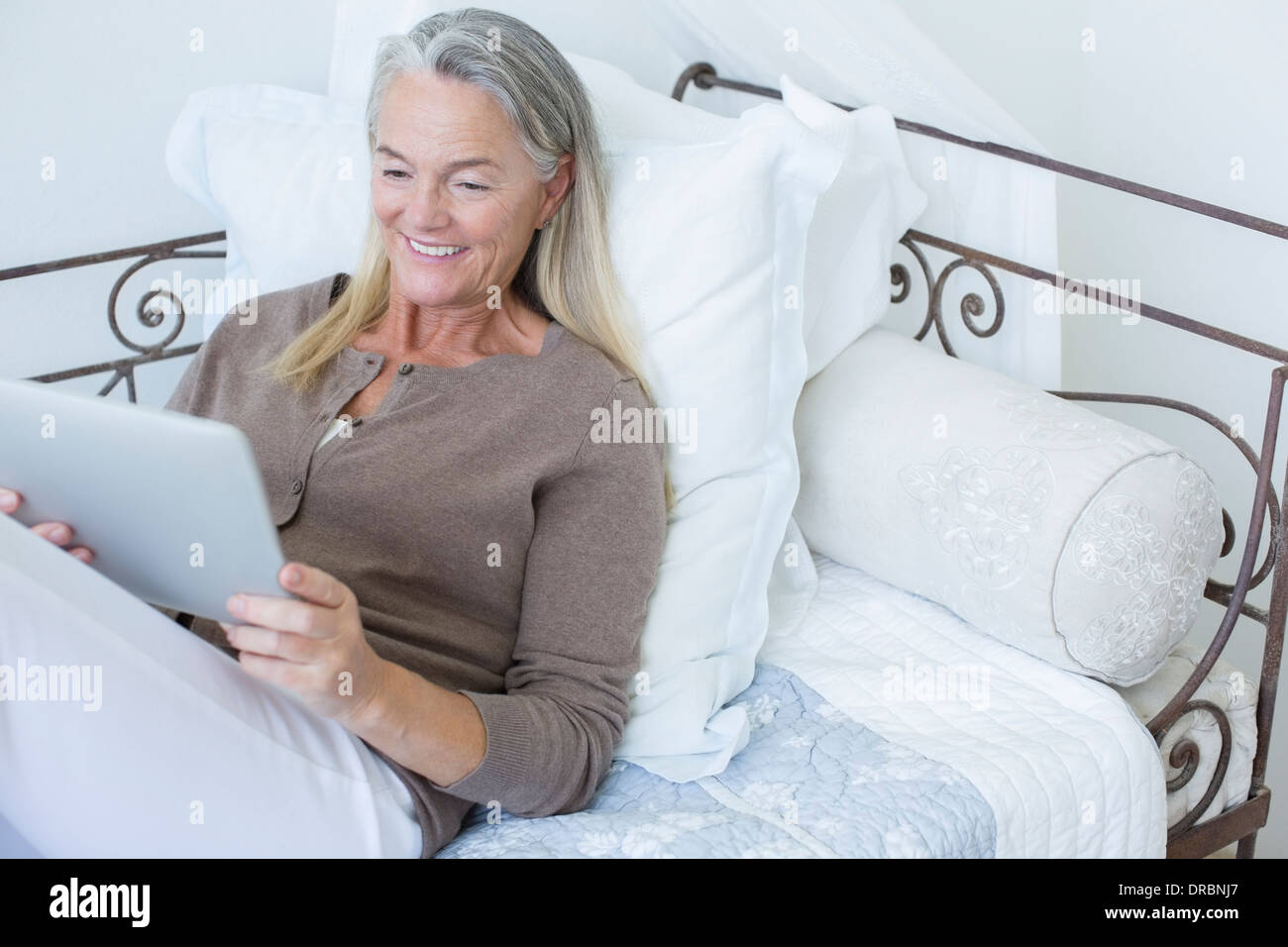 Ältere Frau mit digital-Tablette auf Bett Stockfoto