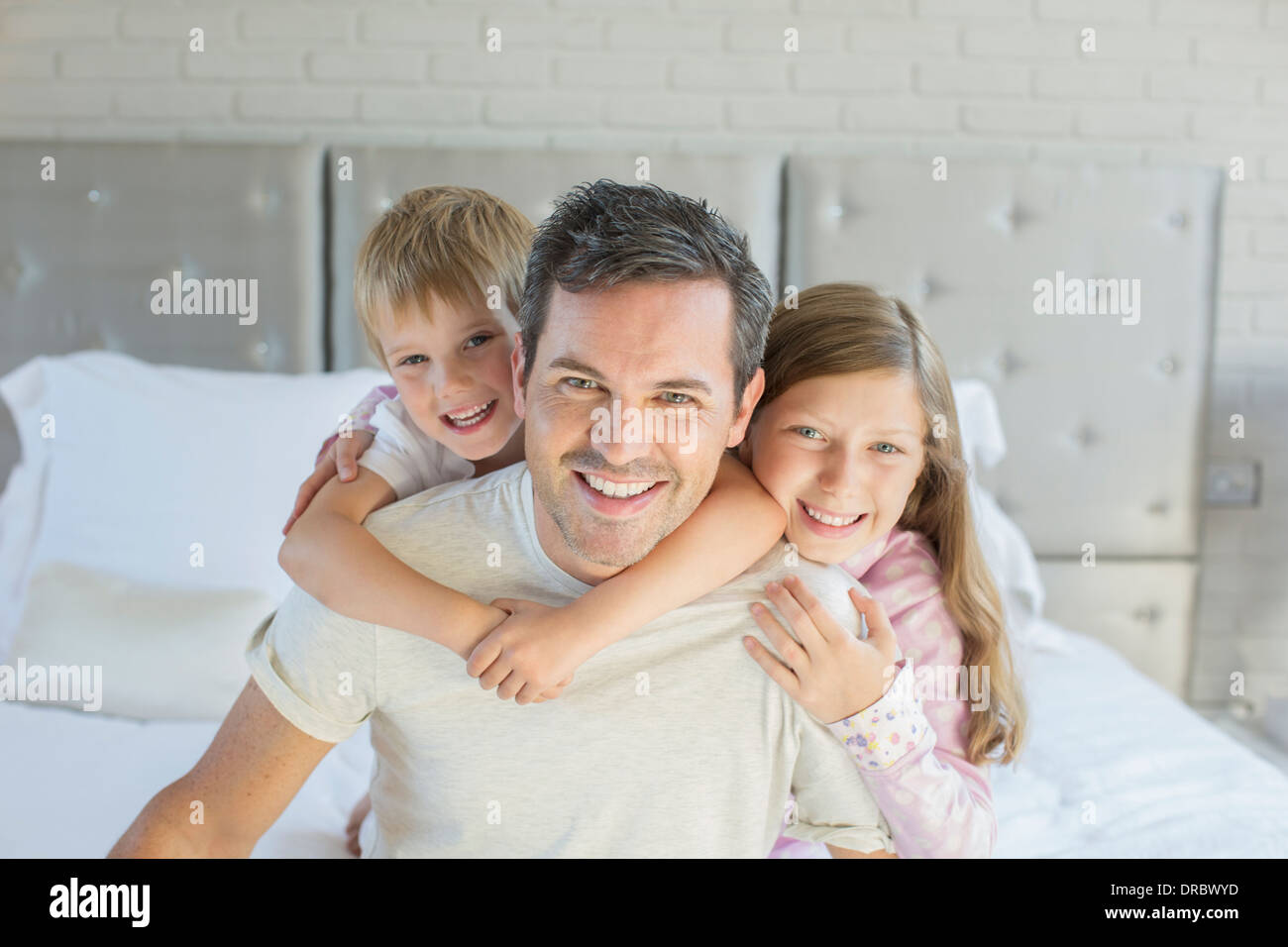 Vater und Kinder umarmen im Schlafzimmer Stockfoto