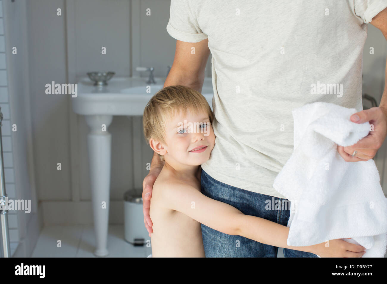 Junge umarmt Vater im Badezimmer Stockfoto