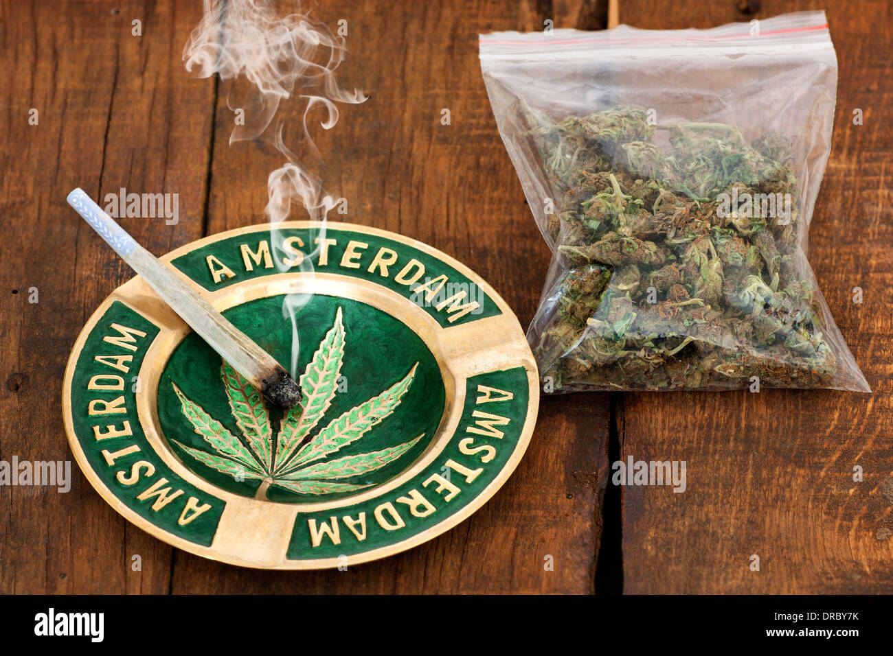 Aschenbecher mit Amsterdam Zeichen und eine große Plastiktüte des Unkrauts auf hölzernen Hintergrund gemeinsame Marihuana rauchen Stockfoto