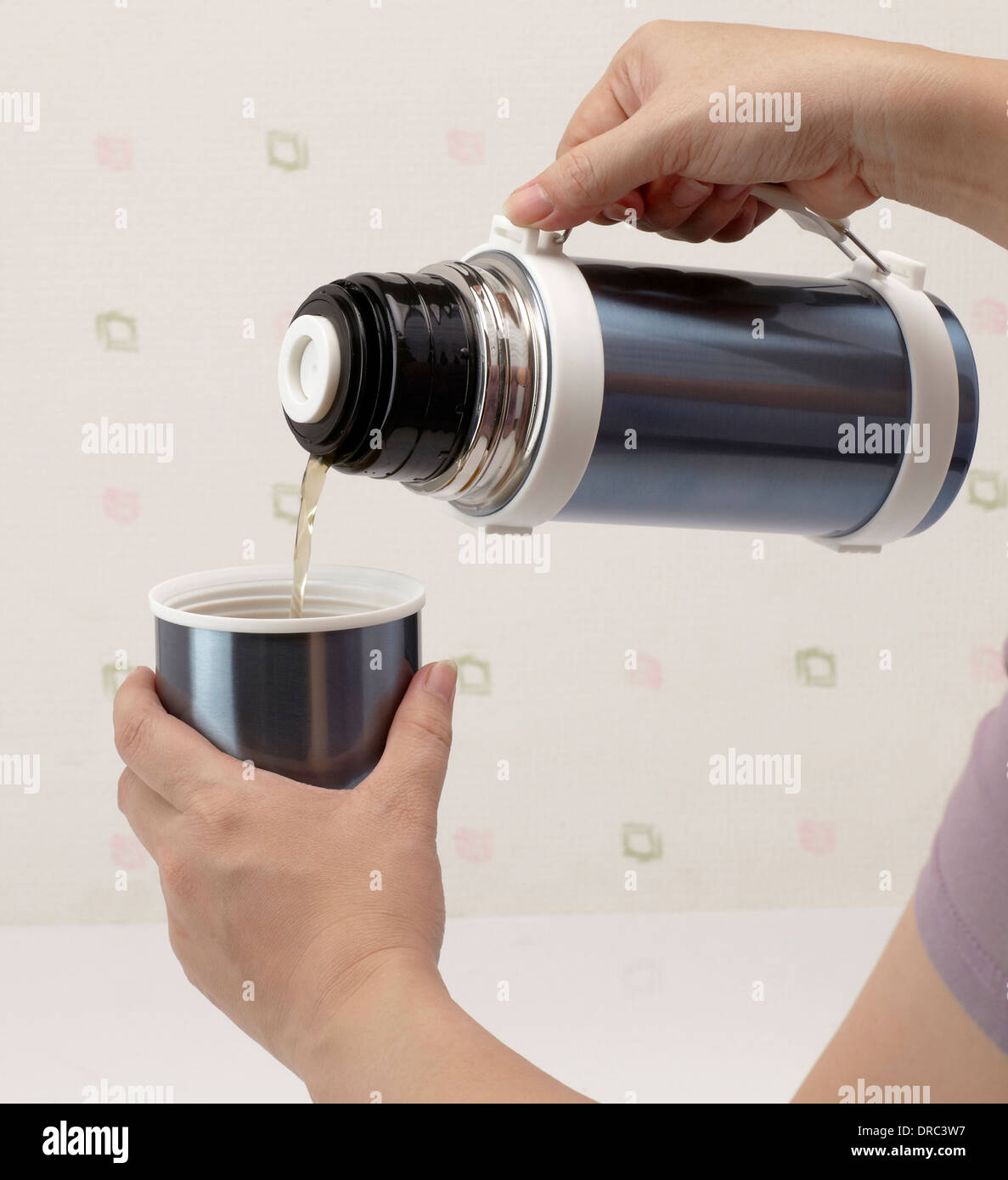 Gießen heißen Tee aus der Thermoskanne in Tasse Stockfoto