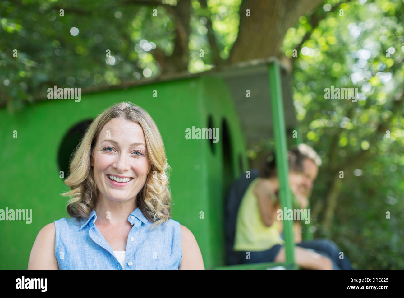 Frau lächelnd mit Baumhaus im Hintergrund Stockfoto