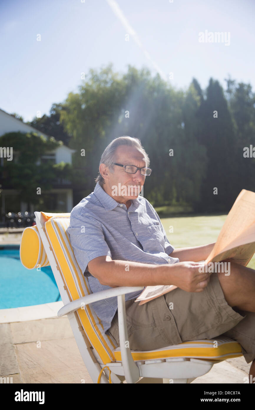 Menschen lesen Zeitung am Pool Stockfoto