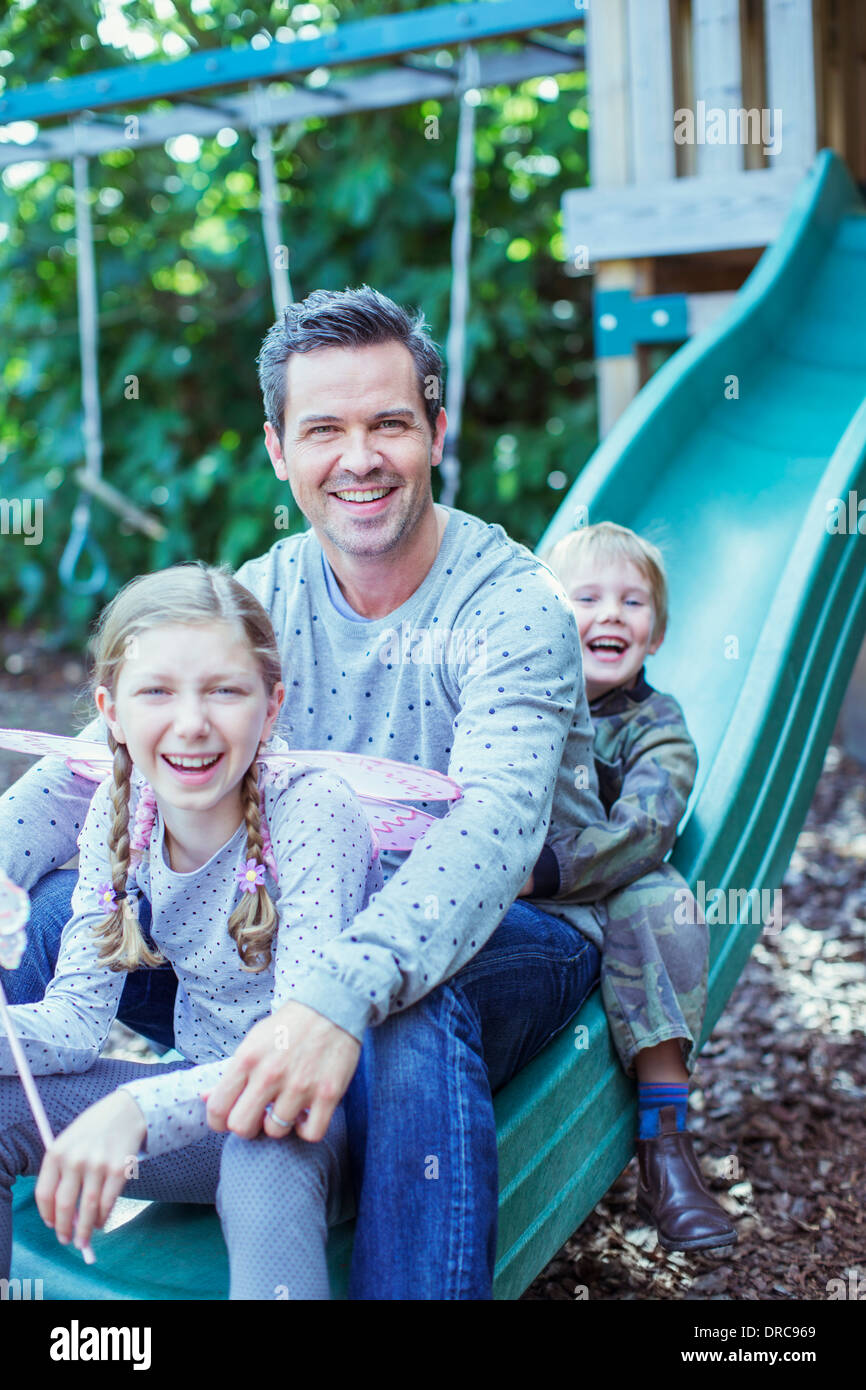 Vater und Kinder sitzen auf Folie Stockfoto