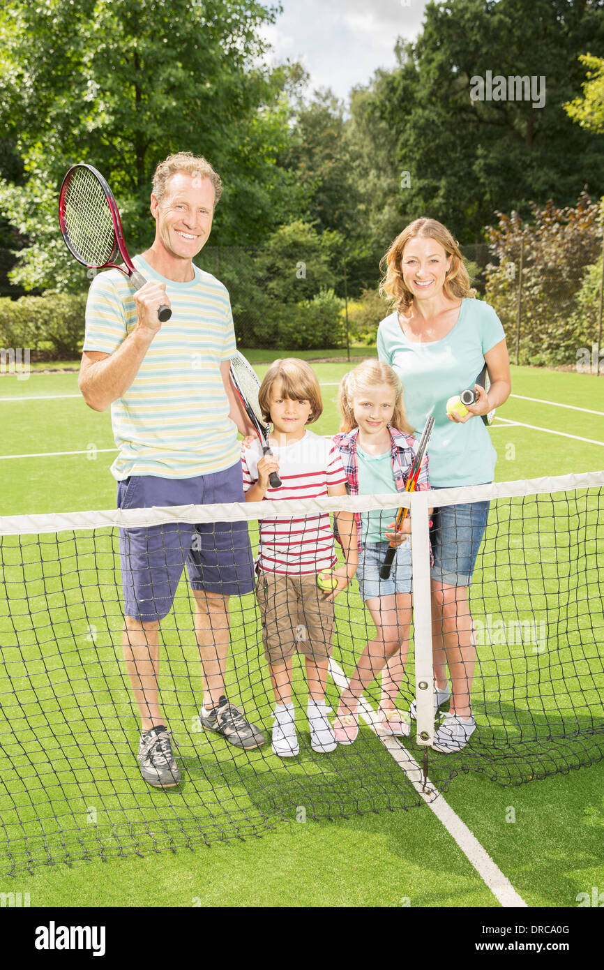 Familie lächelnd zusammen auf Rasentennisplatz Stockfoto