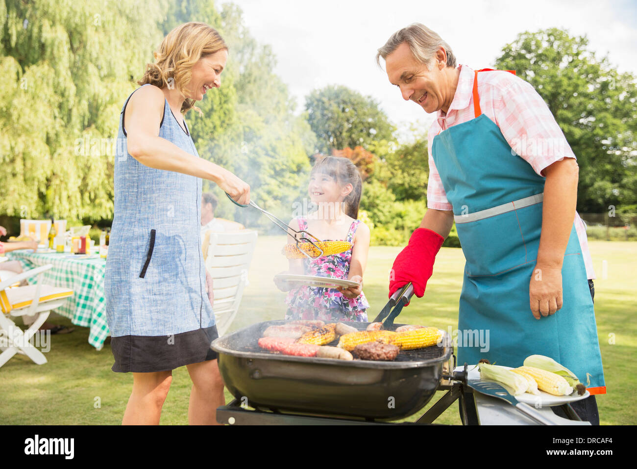 Generationsübergreifende Familie stehen am Grill im Garten Stockfoto